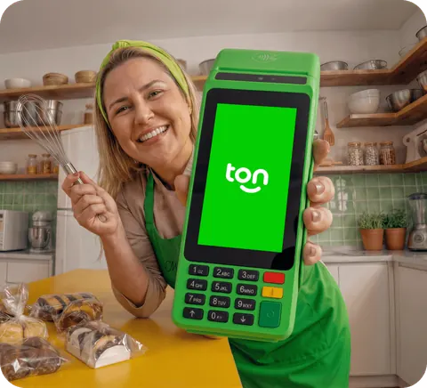 Confeiteira sorrindo na cozinha do seu negócio, mostrando a maquininha T3 Smart